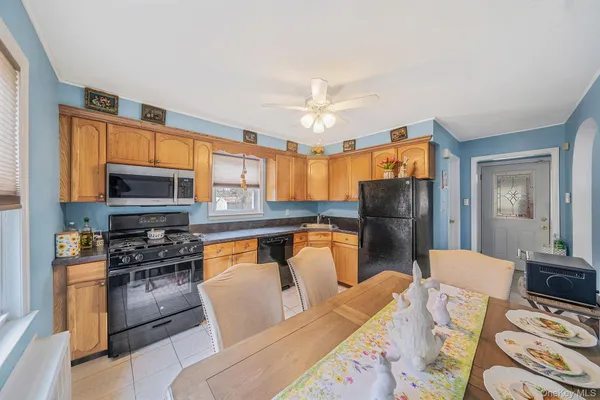 a kitchen with stainless steel appliances granite countertop a stove a refrigerator a sink dishwasher a dining table and chairs with wooden floor