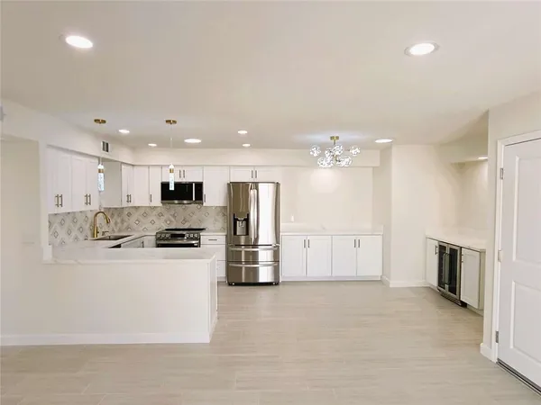 a large white kitchen with a stove a refrigerator and a kitchen island
