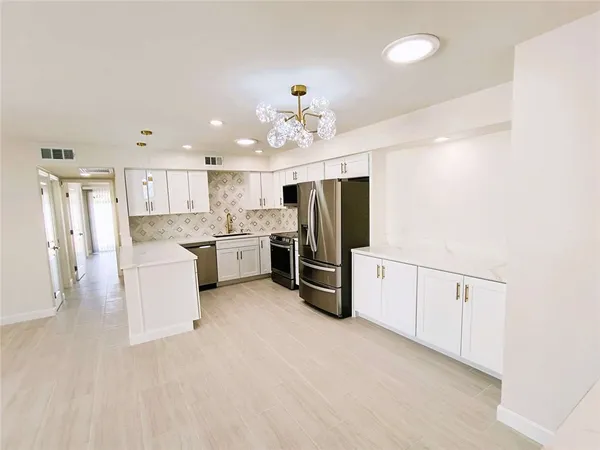 a kitchen with stainless steel appliances granite countertop a refrigerator a sink dishwasher a stove with white cabinets and wooden floor