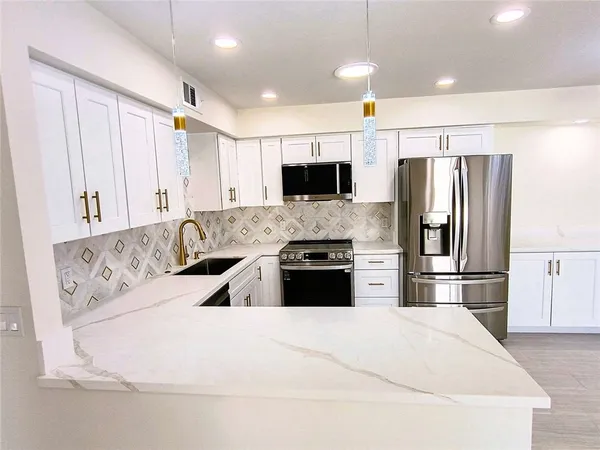 a large white kitchen with stainless steel appliances