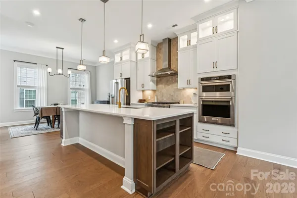 a large kitchen with kitchen island a sink a center island a stove and a wooden floor