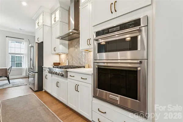 a kitchen with stainless steel appliances granite countertop a refrigerator a stove and a sink with wooden floor
