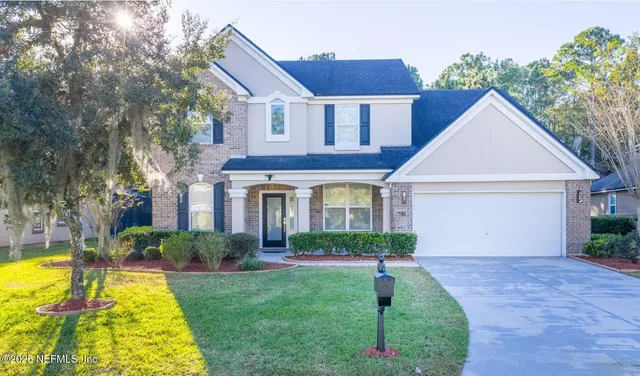 a front view of a house with yard and green space