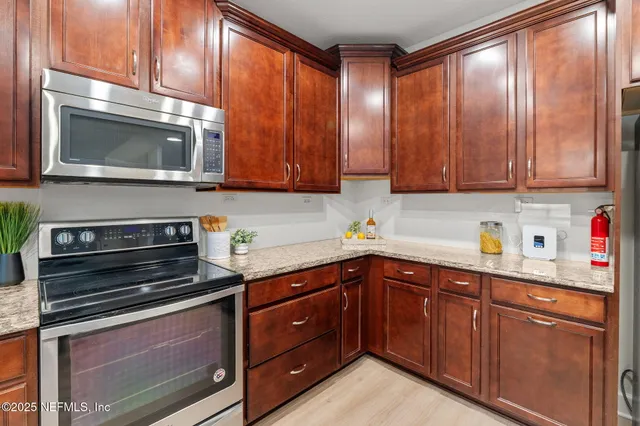 a kitchen with stainless steel appliances granite countertop wooden cabinets and a stove top oven