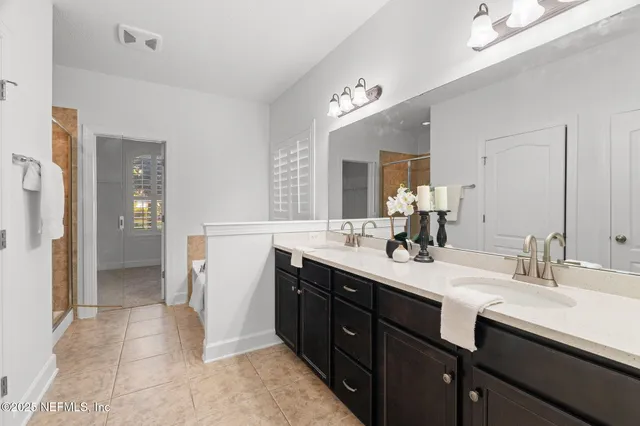 a spacious bathroom with a double vanity sink a mirror and a shower