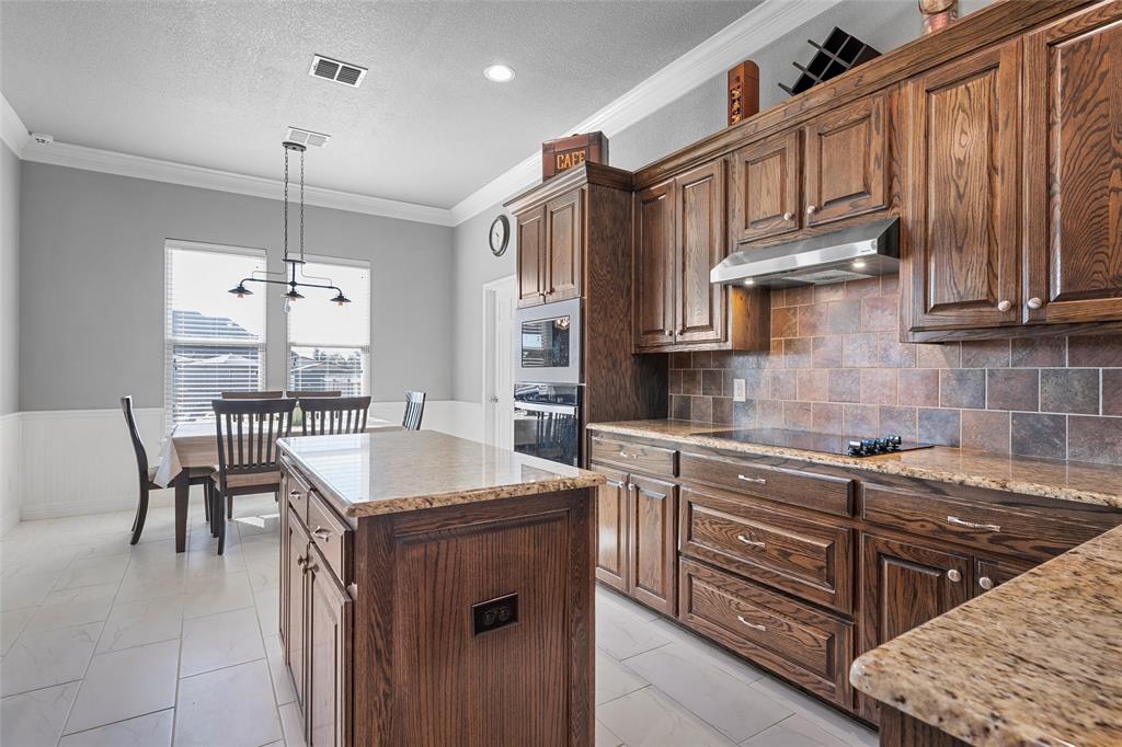 1420 Hoosier Park Robinson, TX 76706 - Photo 11 of 40 Kitchen featuring a center island, decorative backsplash, hanging light fixtures, granite countertops, and under cabinet range hood