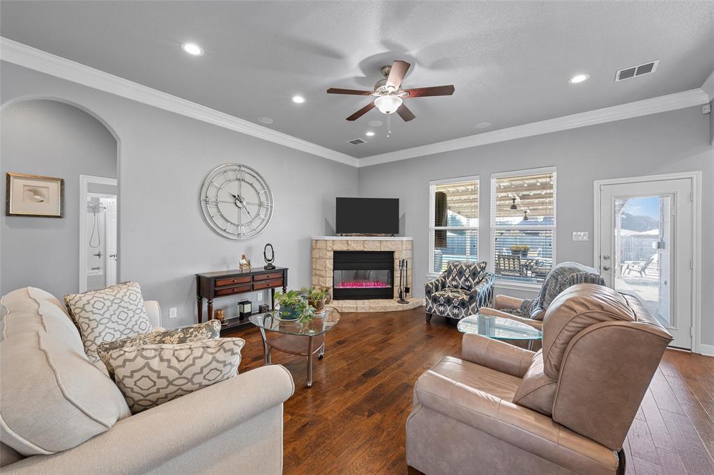 1420 Hoosier Park Robinson, TX 76706 - Photo 3 of 40 Living area featuring crown molding, a stone fireplace, hardwood floors, recessed lighting, and ceiling fan