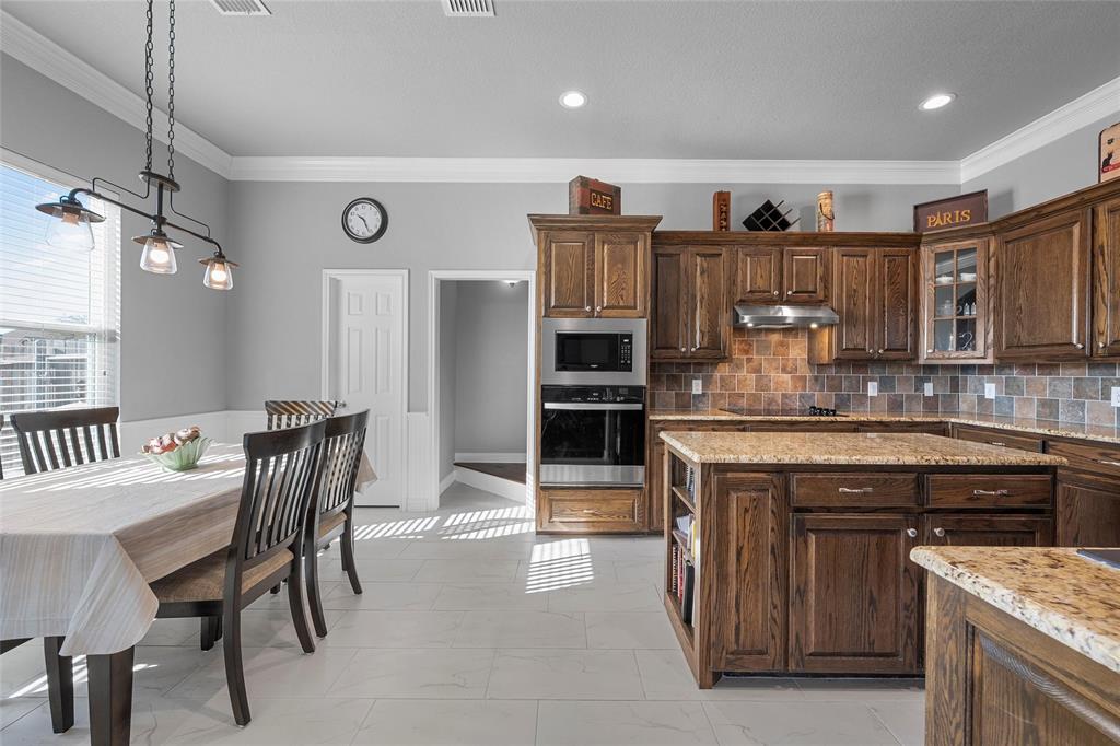 1420 Hoosier Park Robinson, TX 76706 - Photo 8 of 40 Kitchen featuring tasteful backsplash, stained wood cabinets, crown molding, appliances with stainless steel finishes, and granite countertops