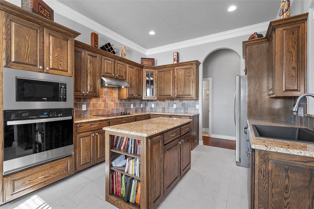 1420 Hoosier Park Robinson, TX 76706 - Photo 9 of 40 Kitchen featuring backsplash, stainless steel appliances, granite countertops, arched walkways, and a center island