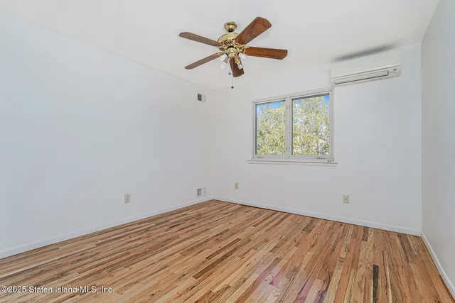 an empty room with wooden floor ceiling fan and windows