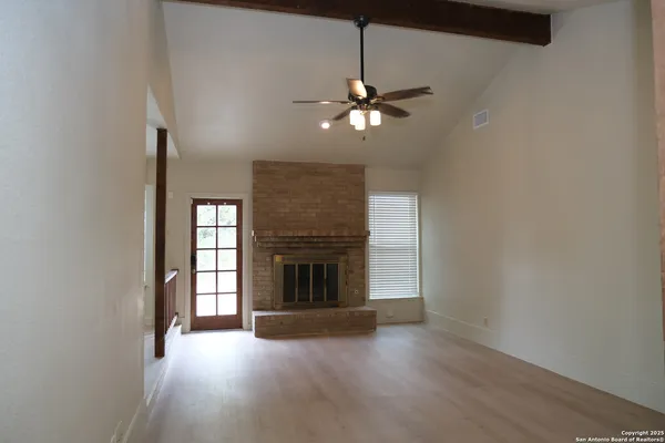 an empty room with windows fireplace and fans