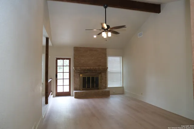 an empty room with windows fireplace and fans