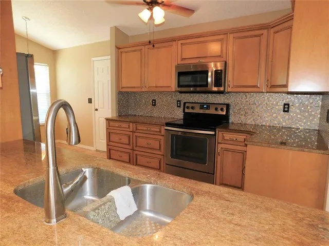 a kitchen with stainless steel appliances granite countertop a stove a sink and a microwave