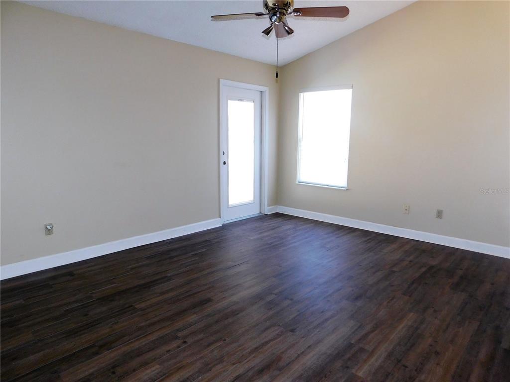 9353 Vía Segovia New Port Richey, FL 34655 - Photo 13 of 25 a view of an empty room with wooden floor and a window