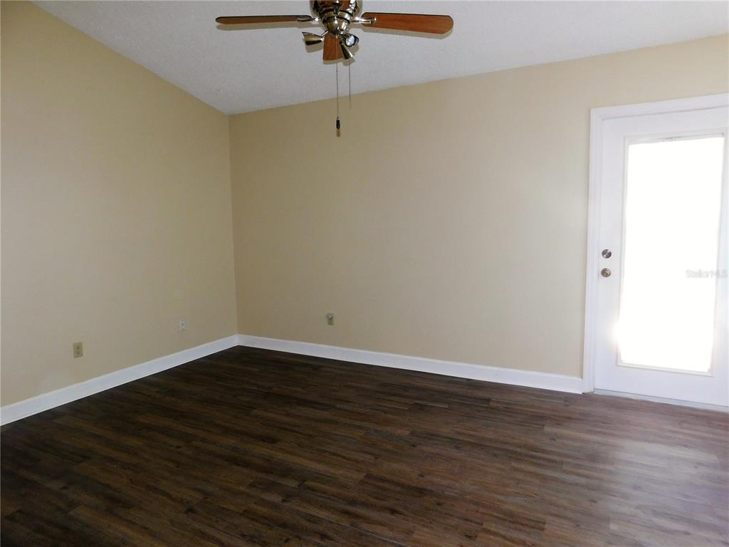 9353 Vía Segovia New Port Richey, FL 34655 - Photo 14 of 25 a view of a room with wooden floor and a ceiling fan