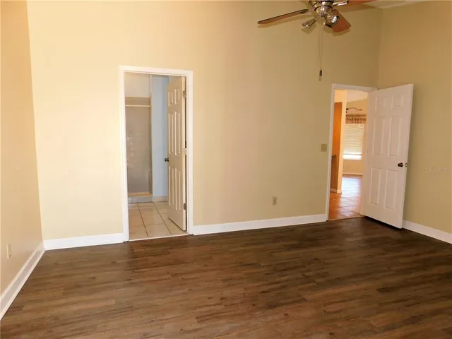 a view of an empty room with a ceiling fan and wooden floor