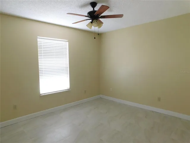an empty room with a window and a fan