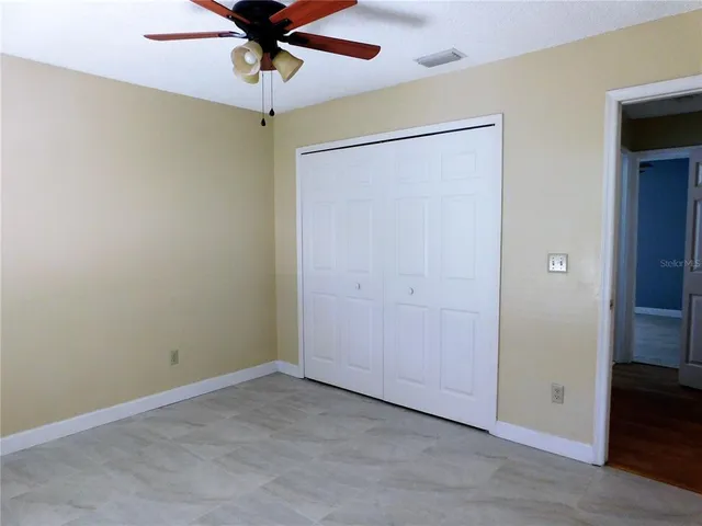 an empty room with closet and a chandelier fan