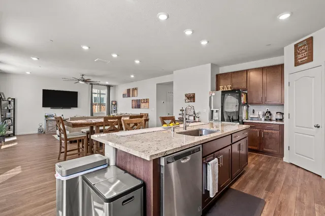 a kitchen with stainless steel appliances granite countertop a stove top oven a sink dishwasher and a dining table with wooden cabinet