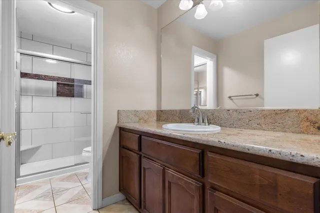 a bathroom with a granite countertop sink a toilet and shower