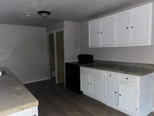 a kitchen with granite countertop white cabinets and black appliances