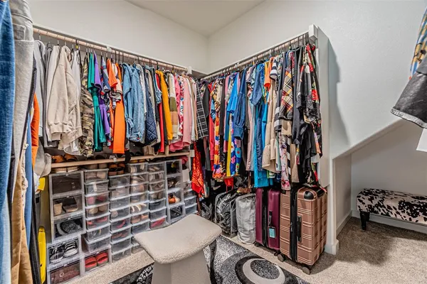 a view of walk in closet with clothes and shoes