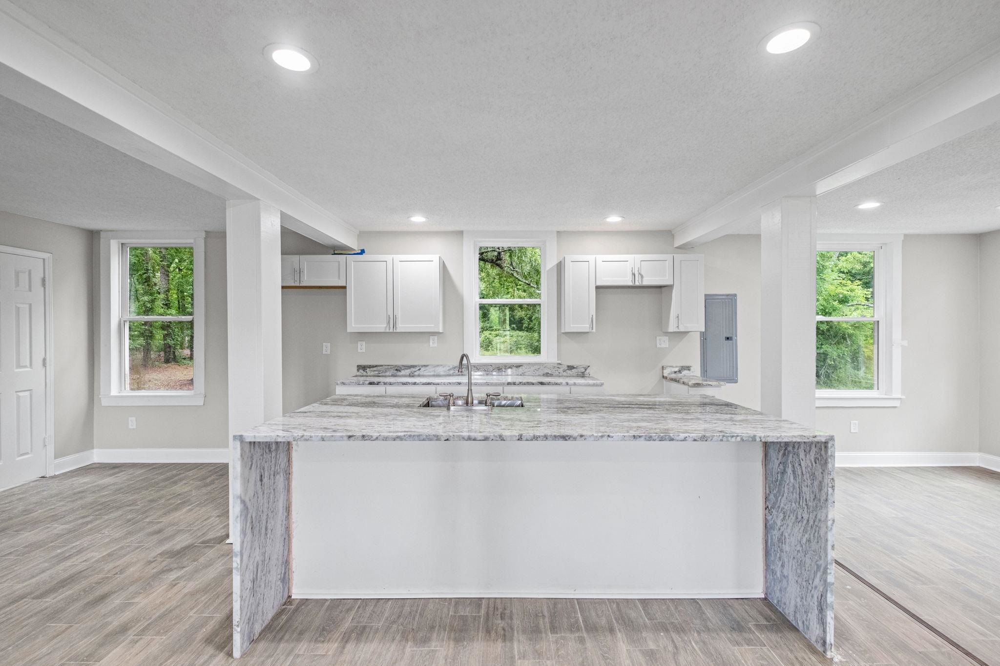 5843 Stewart Road Lakeland, TN 38002 - Photo 13 of 26 Central kitchen island with waterfall-edge countertop, white cabinetry, and recessed lighting
