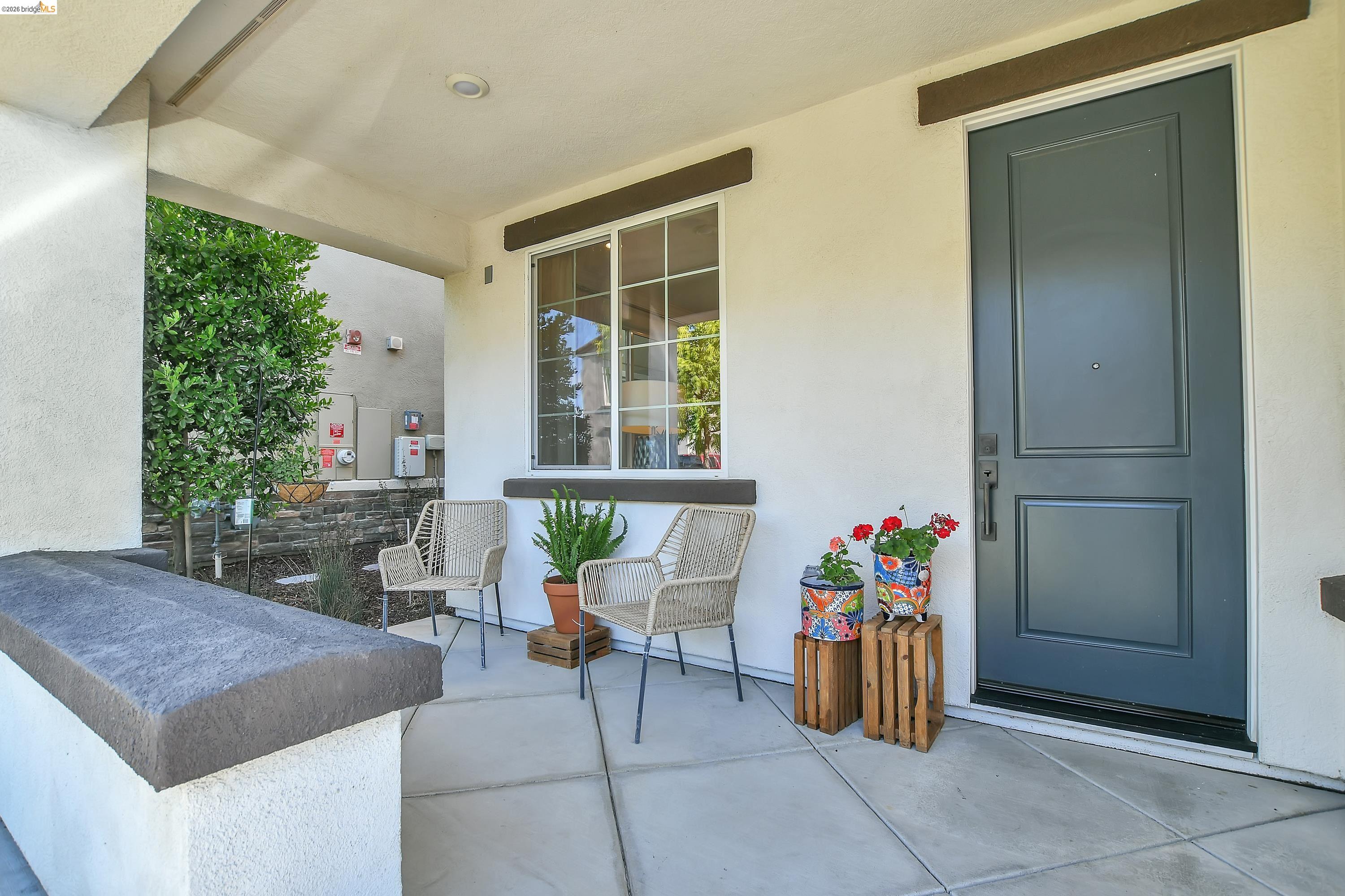 Covered front porch featuring a paneled entry door with dark hardware, recessed lighting, and a front-facing window