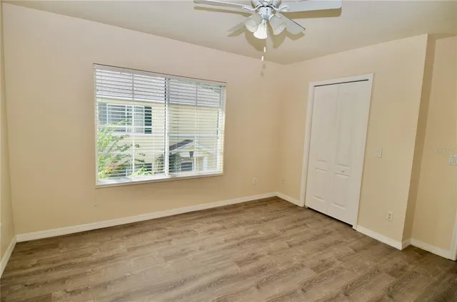 a view of an empty room with wooden floor and a window