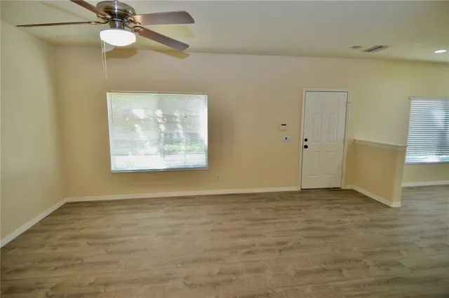 an empty room with a ceiling fan and window