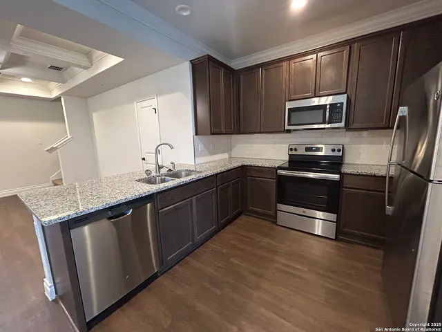a kitchen with stainless steel appliances granite countertop a sink stove microwave and refrigerator