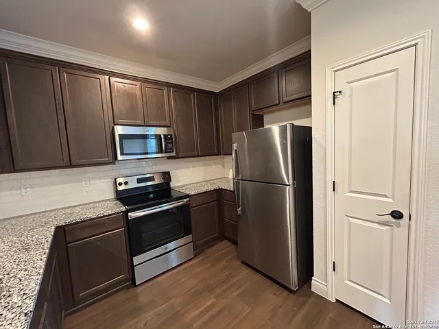 a kitchen with granite countertop wooden cabinets and stainless steel appliances