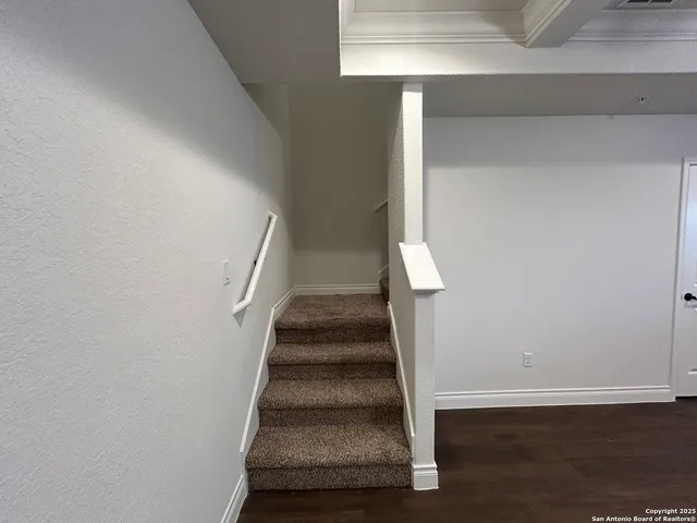 a view of staircase with wooden floor and white walls