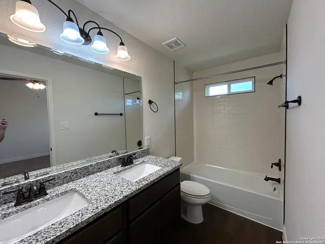 a bathroom with a granite countertop sink a toilet and shower