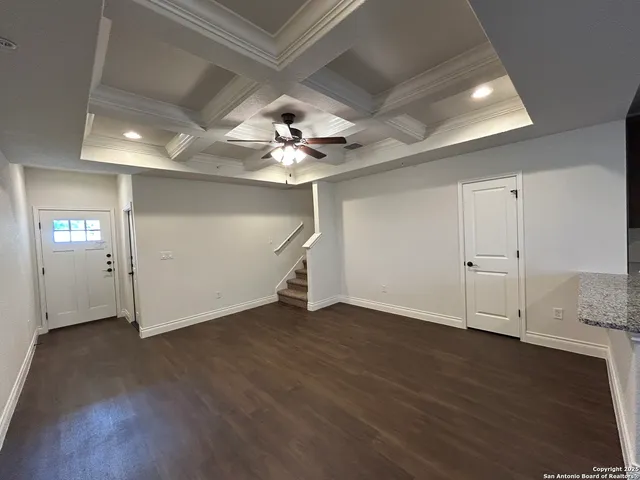 an empty room with wooden floor and ceiling fan