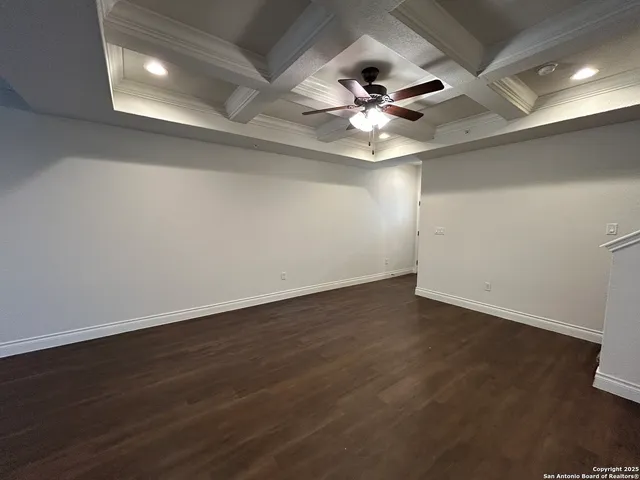 an empty room with wooden floor and fan