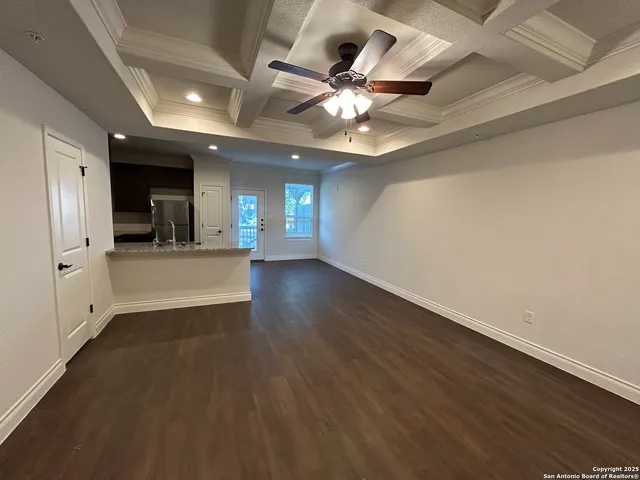 an empty room with wooden floor and ceiling fan
