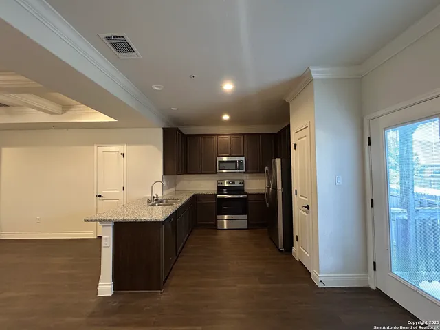 a kitchen with kitchen island granite countertop a sink counter top space and stainless steel appliances
