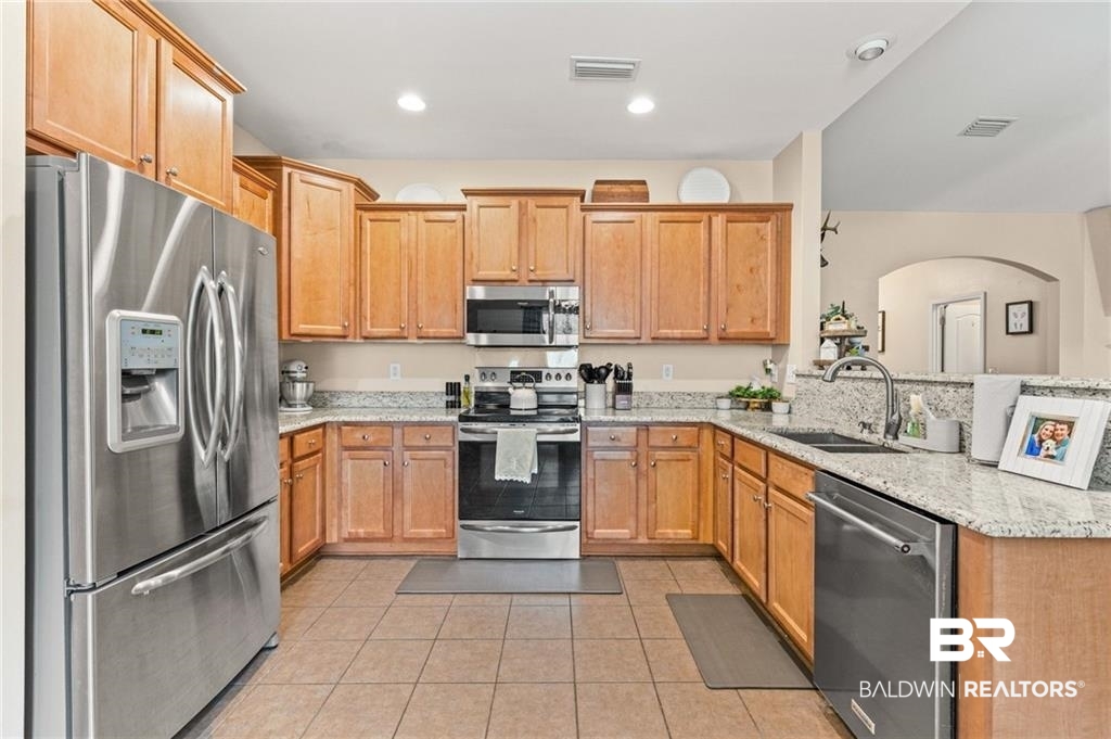 2570 Pecan Pointe Drive Semmes, AL 36575 - Photo 6 of 22 Kitchen with stainless steel appliances, light stone counters, light tile patterned floors, wood finish cabinetry, and recessed lighting