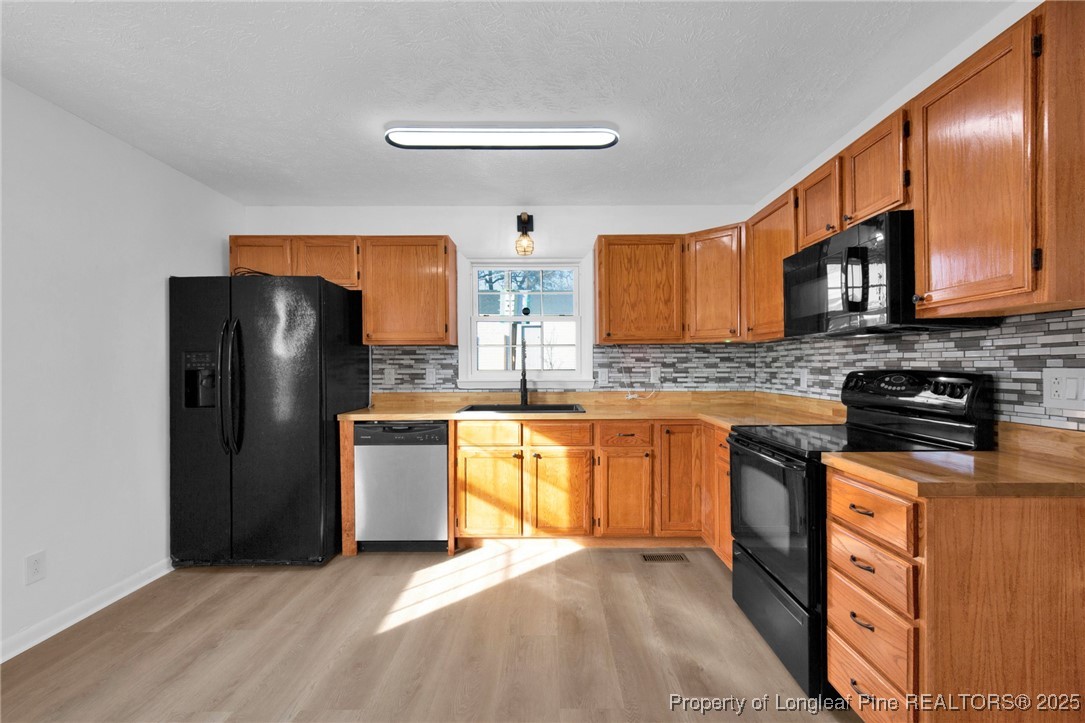6806 Beaver Stone Road Fayetteville, NC 28314 - Photo 14 of 42 a kitchen with stainless steel appliances granite countertop a refrigerator stove top oven a sink and dishwasher