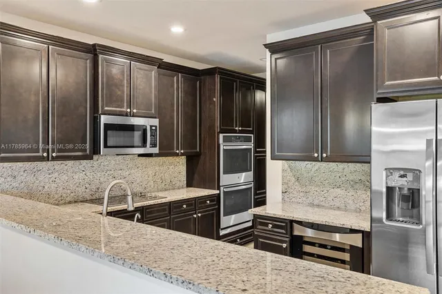 a kitchen with stainless steel appliances granite countertop a refrigerator and a stove top oven
