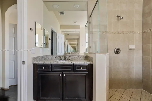 a bathroom with a granite countertop shower a mirror and a sink