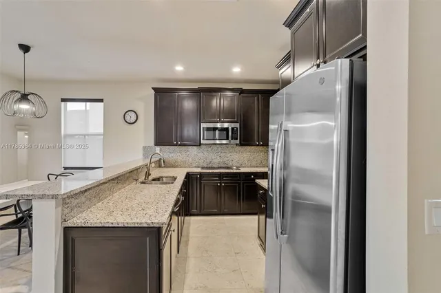 a kitchen with granite countertop a refrigerator and a sink