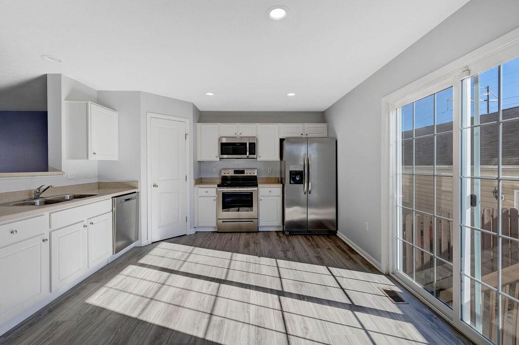6345 Needletail Road, Unit 24634 Columbus, OH 43230 - Photo 8 of 58 • New luxury vinyl plank flooring ~ 2021 • Gray painted walls • Bevelled edge countertops • White, raised panel cabinets • Double bowl, stainless steel sink • New Frigidaire® dishwasher ~ 2021 • New Frigidaire® electric range ~ 2021 • New Frigidaire® microwave ~ 2021 • New Frigidaire® refrigerator ~ 2021 • Step-in pantry closet • Can lighting • Insinkerator® disposal • New double sliding doors (2020) to privacy fenced, paver patio