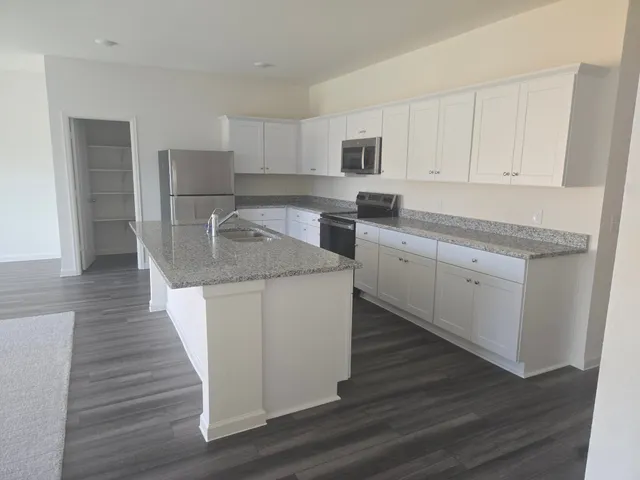 a kitchen with kitchen island white cabinets appliances and sink