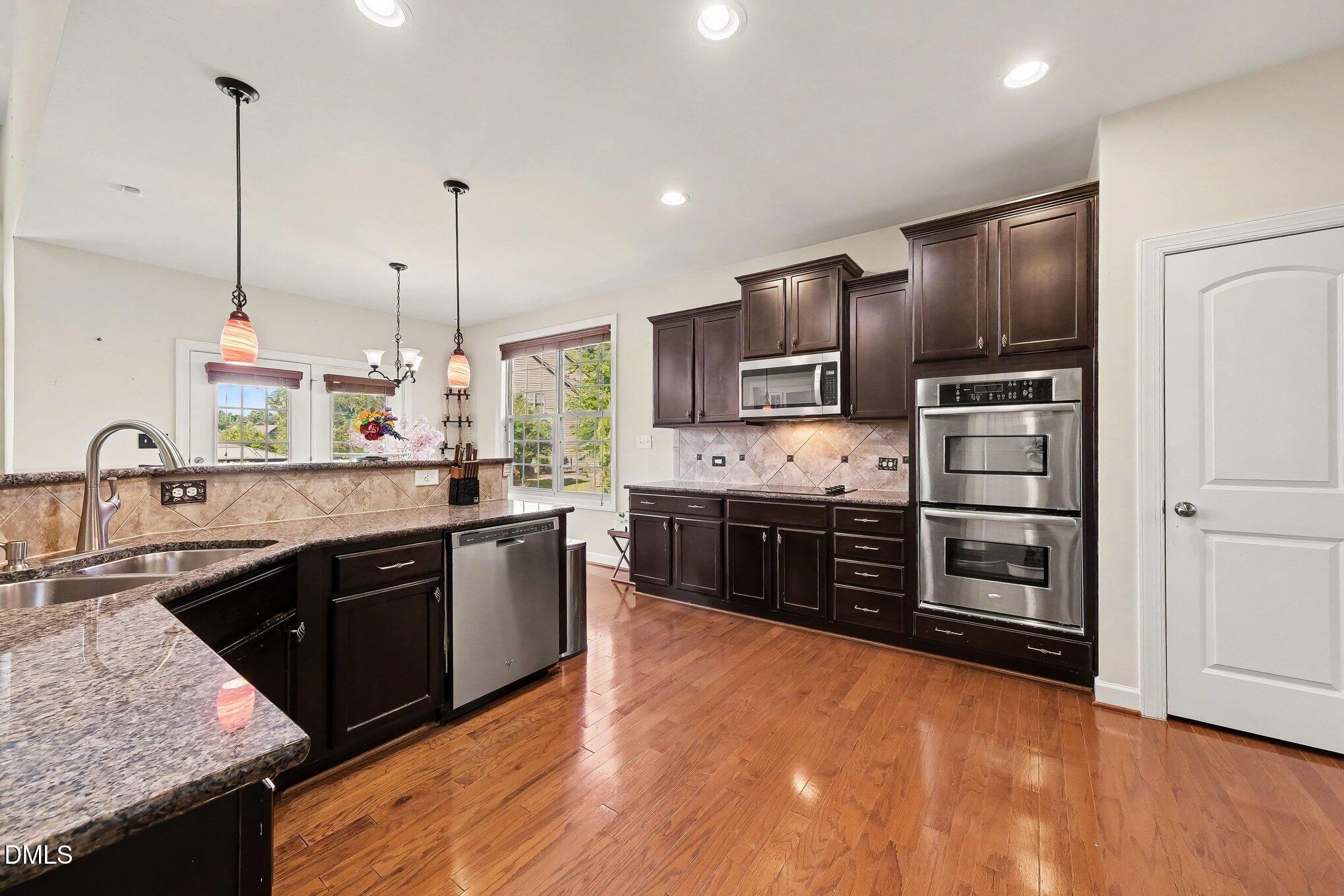 4000 Banks Stone Drive Raleigh, NC 27603 - Photo 7 of 60 a large kitchen with stainless steel appliances kitchen island granite countertop a stove a refrigerator a sink a microwave and wooden floor