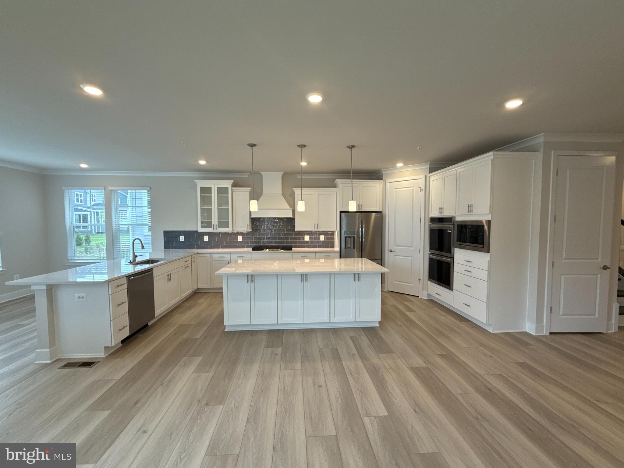 116 Stilly Way Annapolis, MD 21403 - Photo 4 of 21 a large kitchen with kitchen island a sink dishwasher a refrigerator and white cabinets with wooden floor
