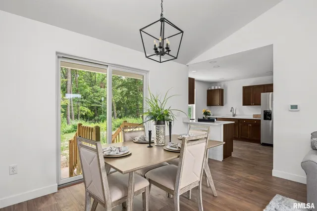 a dining room with wooden floor a chandelier a wooden table and chairs