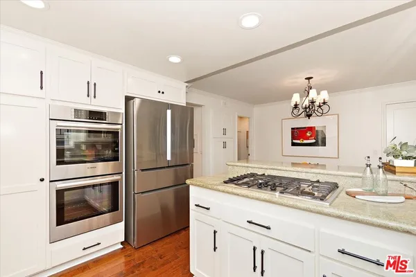 a kitchen with stainless steel appliances granite countertop a refrigerator and a stove top oven