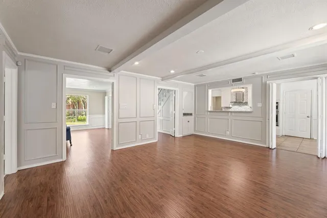 a view of an empty room with window and wooden floor